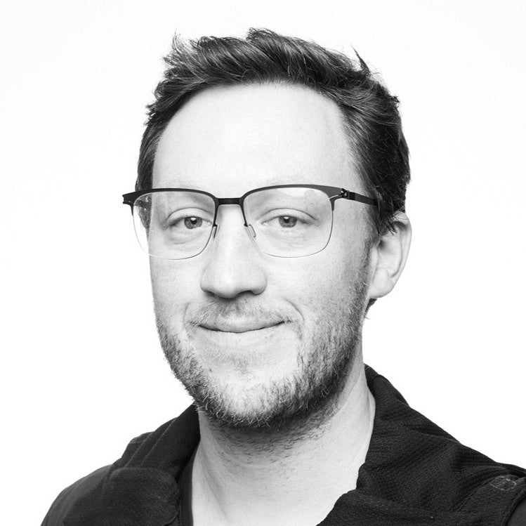 Profile Photo of SAE Assistant Professor, Dylan Wood. Shows a smiling man with styled hair wearing glasses and stubble/short beard.