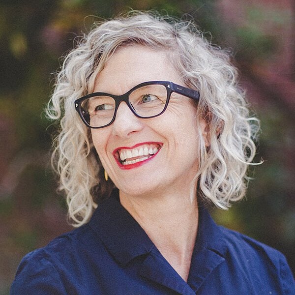 Photograph of Liska Chan. Shows a woman with glasses smiling to the left hand side of the photo at someone off camera. 