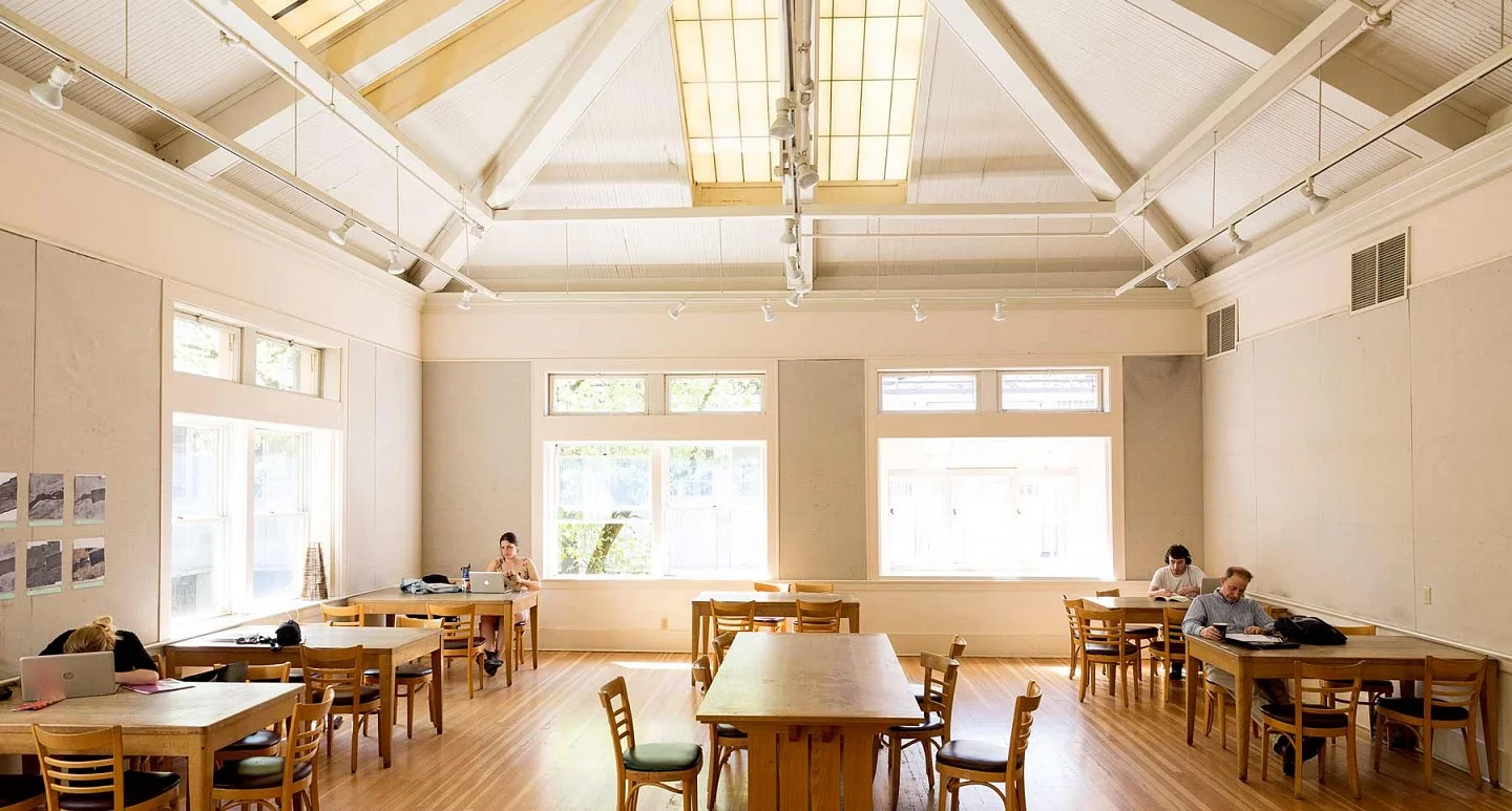 The Wilcox Hearth with vaulted ceiling, wood floor, and students studying at tables