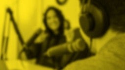 Generic photo of two people in a radio interview setting. Made black and white with a yellow color over the top and a blurry filter. 