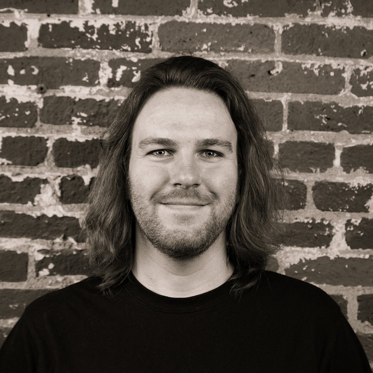 Photograph of a smiling first-year SPD student, Joe Waits, in front of a brick wall.