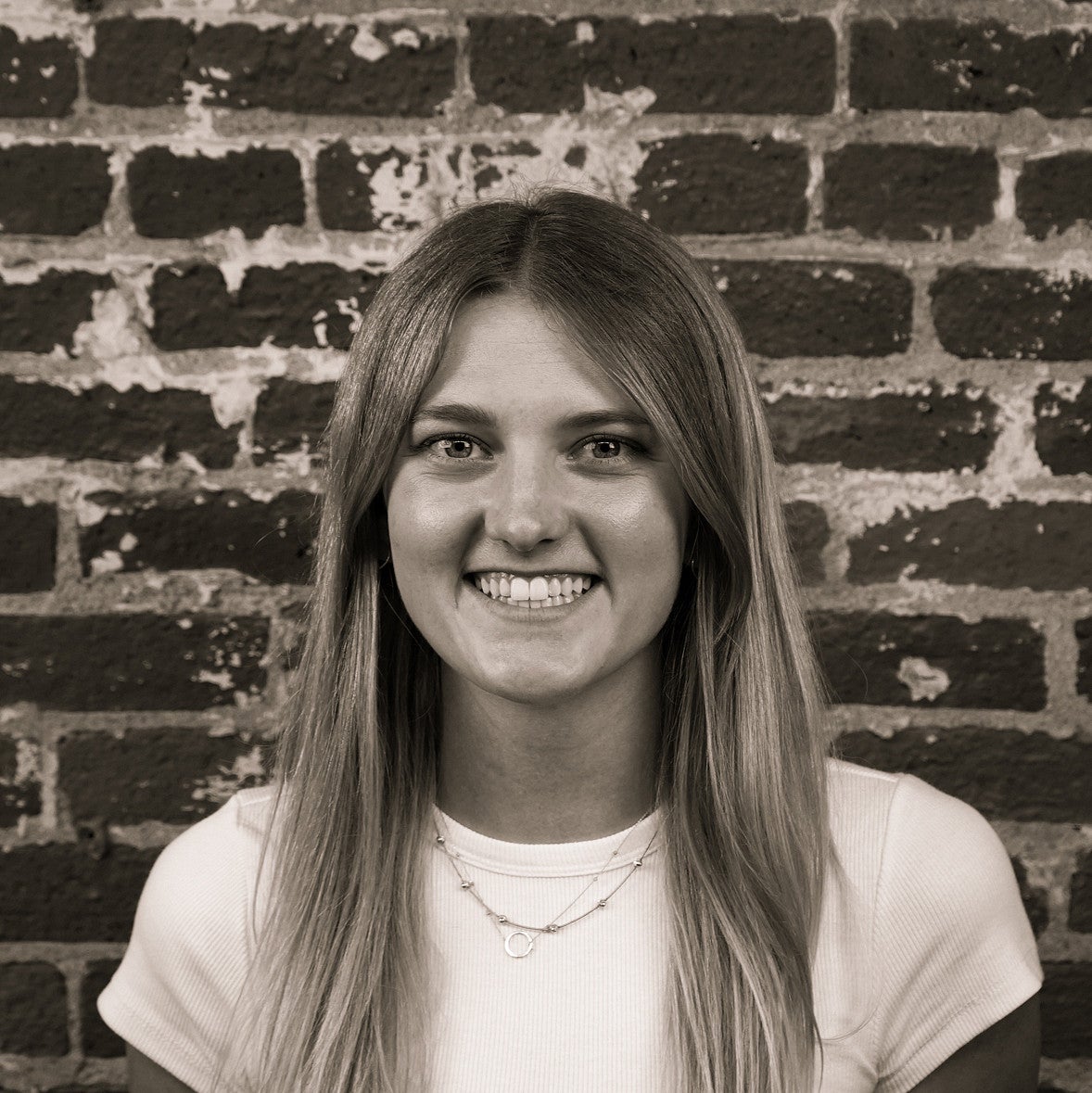 Photograph of a smiling first-year SPD student, Makena Klatt, in front of a brick wall.