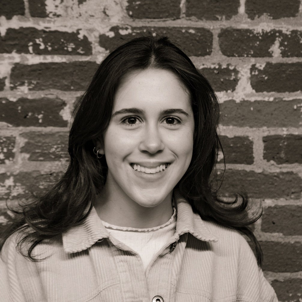 Photograph of a smiling first-year SPD student, Sara Valeri, in front of a brick wall.