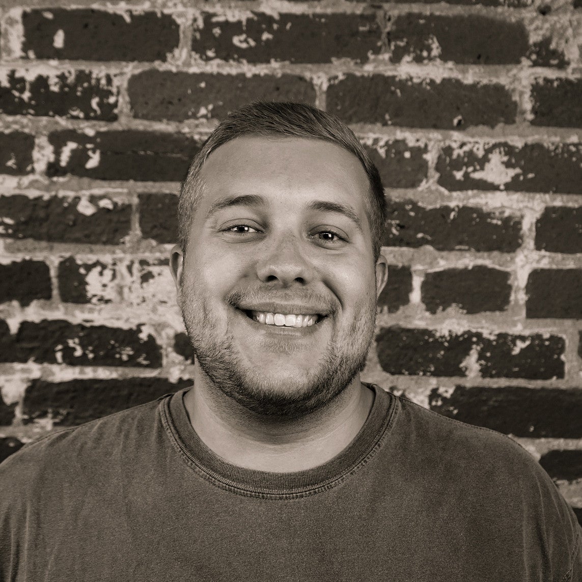 Portrait photo of smiling SPD student Sky Bunker in front of a brick wall.