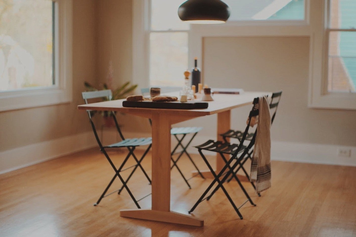 Photograph of Tom's work, Adam's Table. Shows a well light, wood featured room with a slim, wooden table and four slim chairs. 
