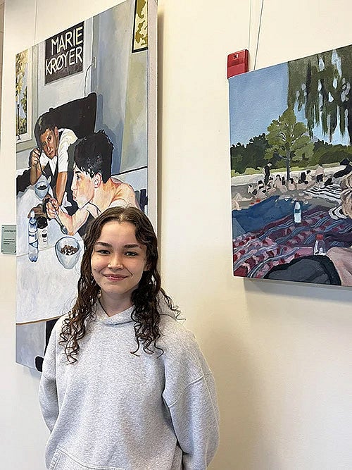 Photo of Ava Murakami in front of her paintings. 