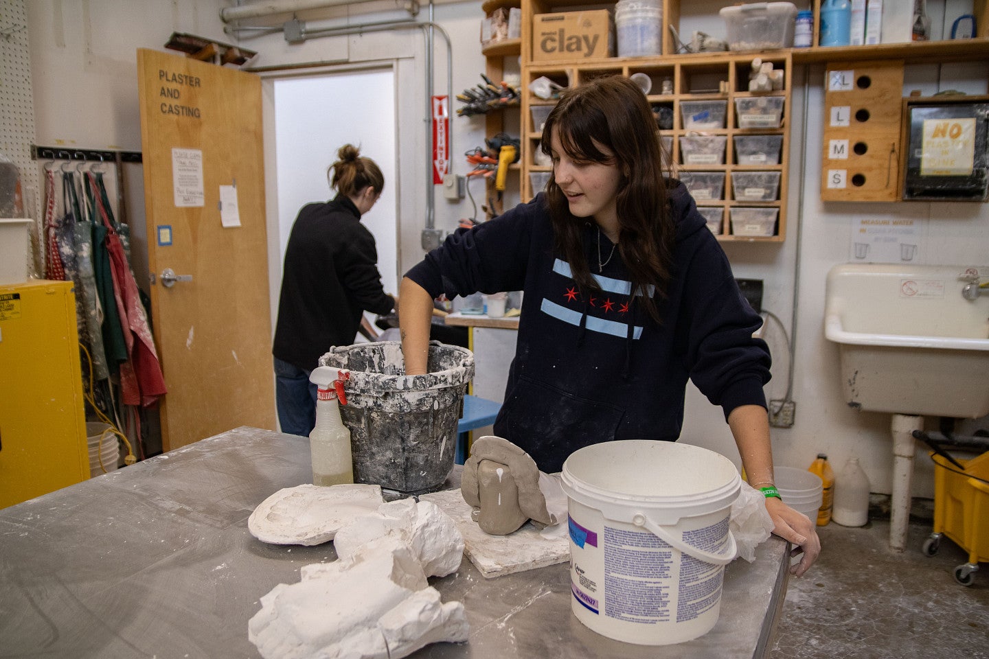 Student works with wet materials in Sculpture studio. Decorative. 