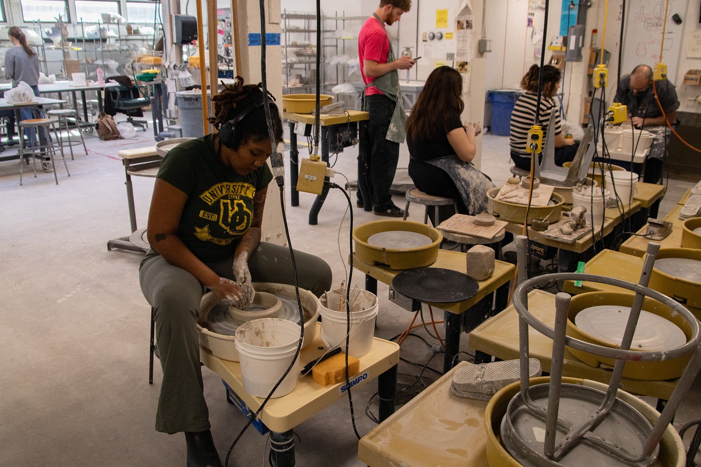 Student works on a pottery wheel. Decorative. 