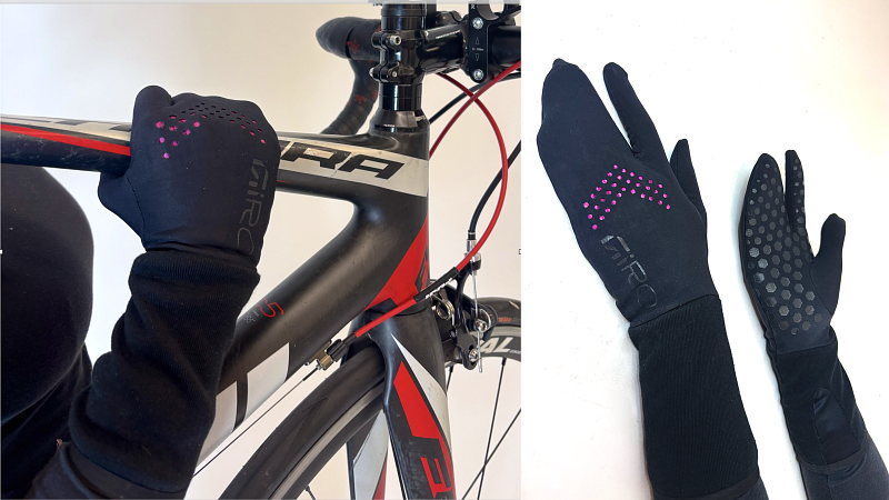 A pair of black, lobster-style glove, meaning the middle, ring, and pinky fingers are all covered by one section. The gloves are meant for warm weather, and have hexagonal, rubbery grips and pink vent holes.