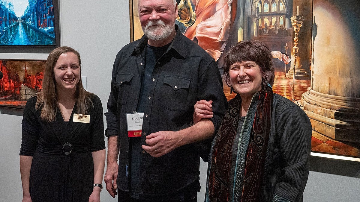 Three people standing in front of a wall of paintings