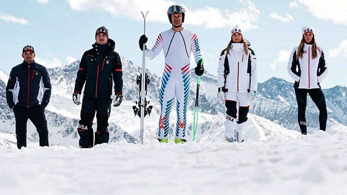people stand in snow wearing Winter Olympics gear. Image source: The Conversation.