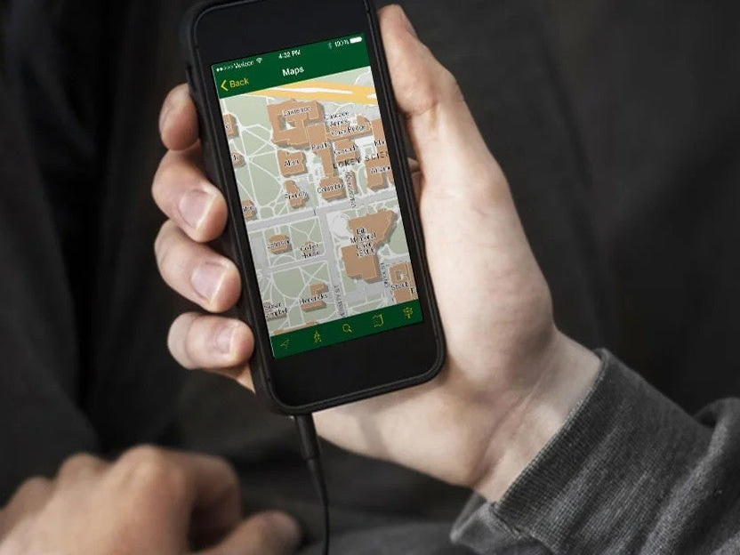 A person's hand holding a phone with the UO map app on it