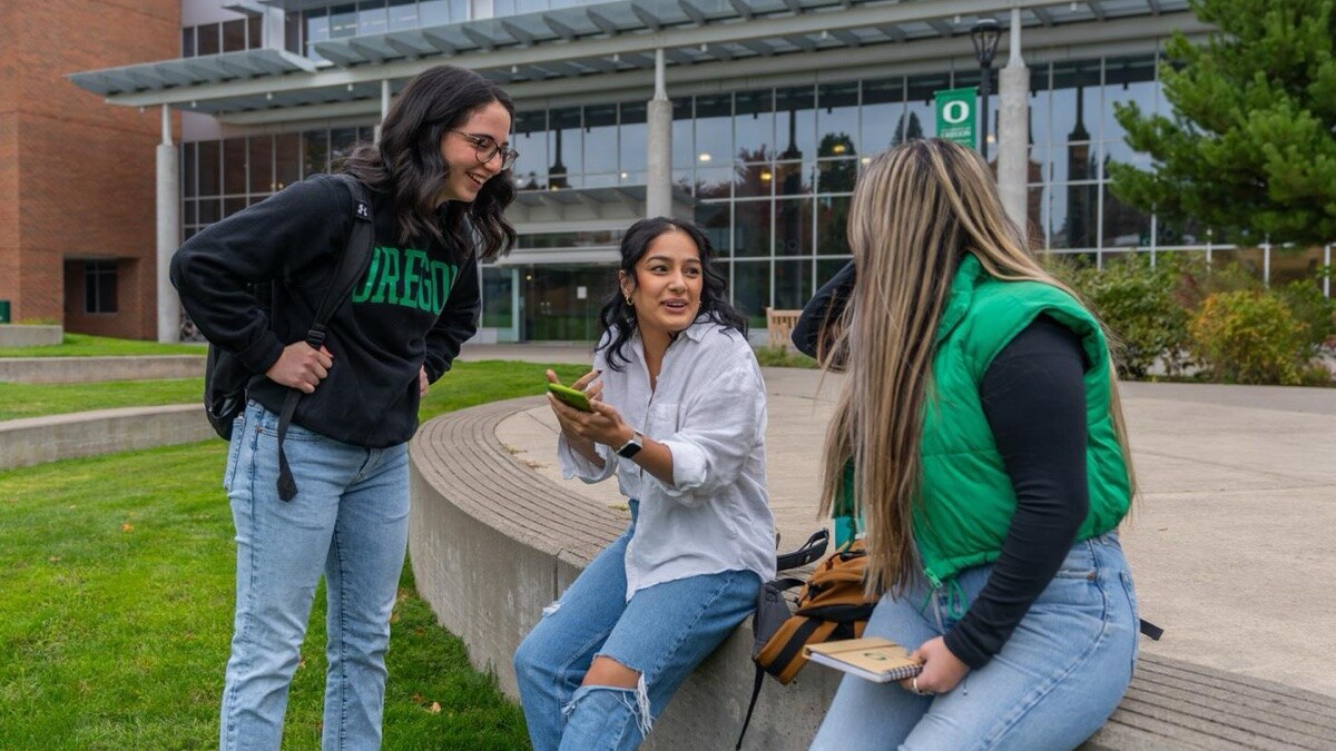 Three students sitting outside at the Portland campus and talking