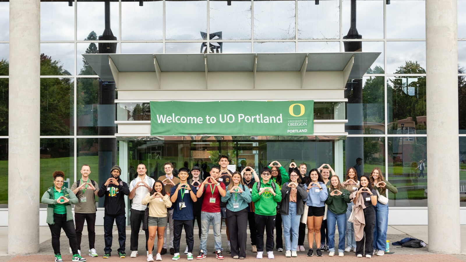 Students pose beneath a Welcome to UO Portland sign.