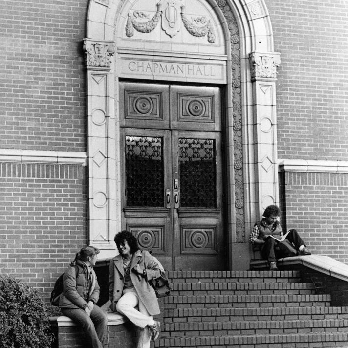 Black and white image of the entrance to Chapman Hall with students on the front steps