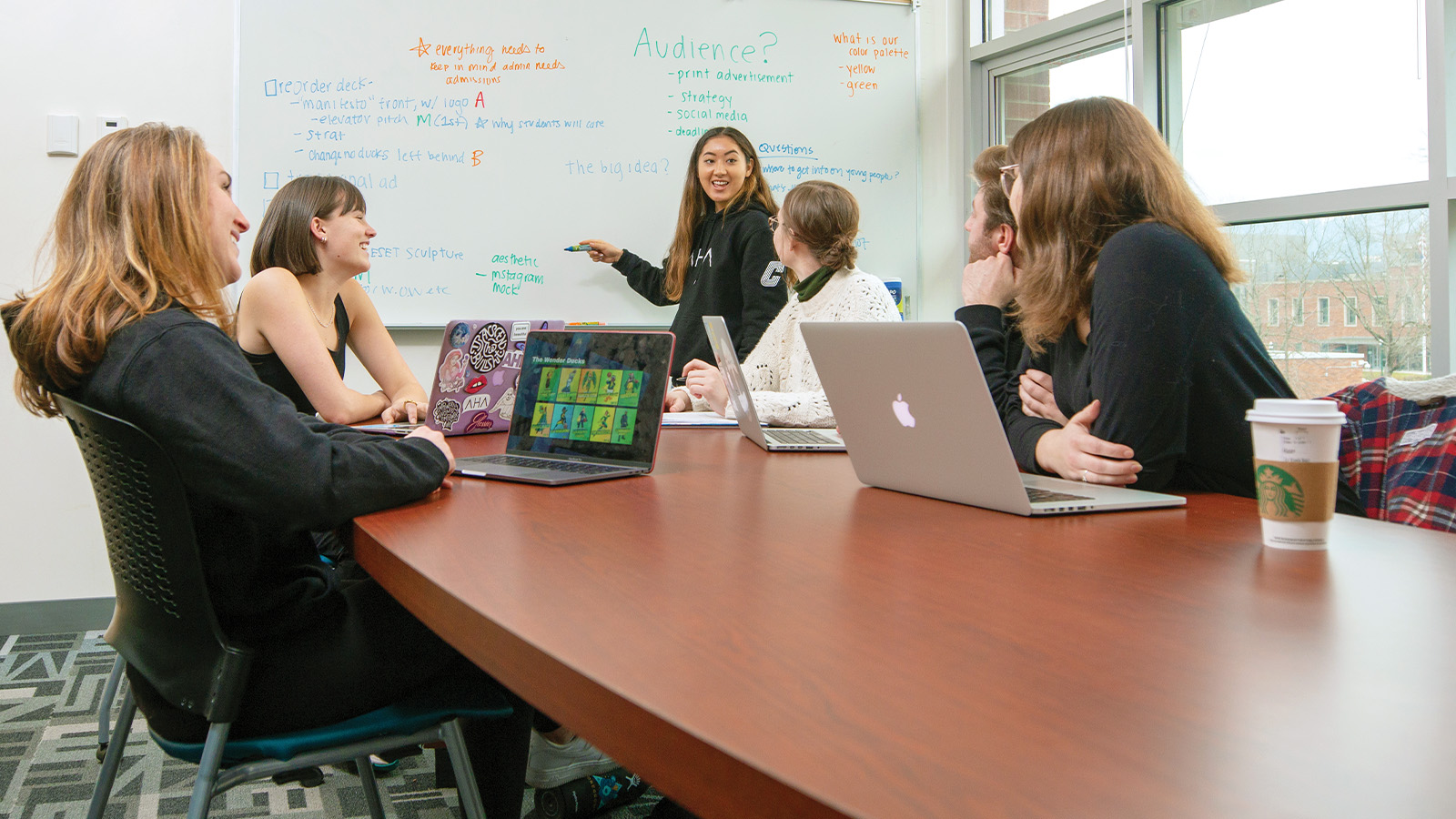 Six students at a table working on digital marketing plans