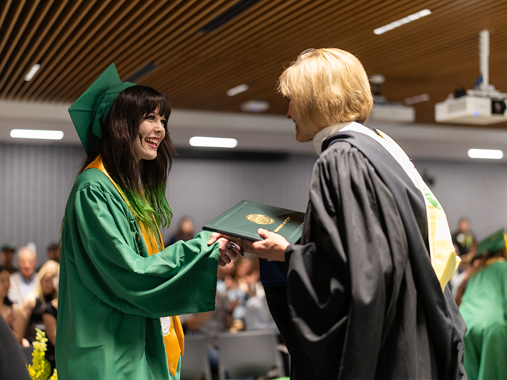Ballmer student graduating and shaking the Dean's hand while getting their diploma