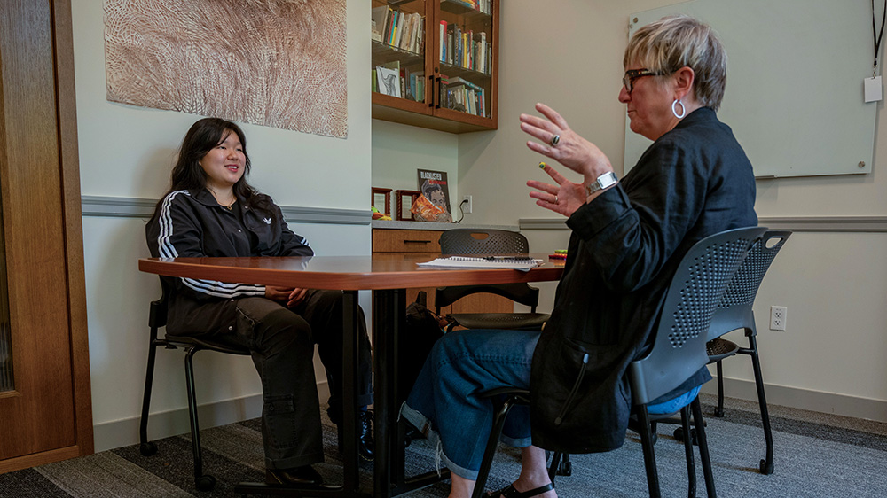 Faculty Advisor talking to a student at a table