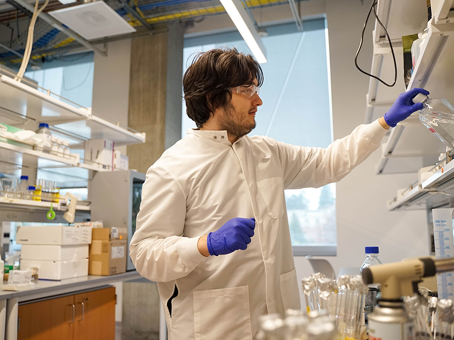 A student reaching for an instrument in a lab