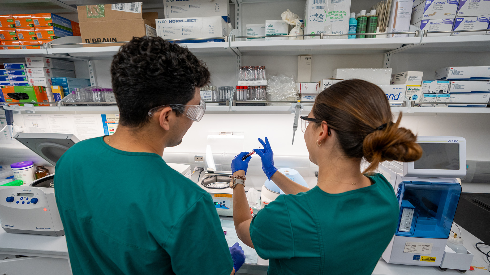 Two researchers in scrubs examining a blood sample