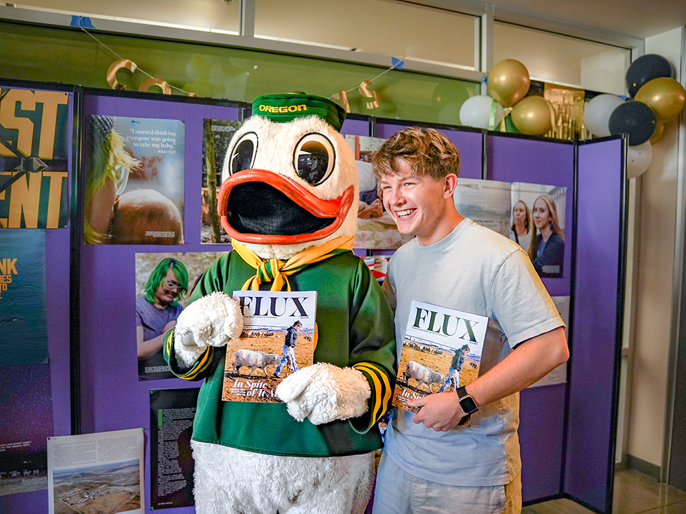 Student standing with the Duck mascot holding up Flex magazine