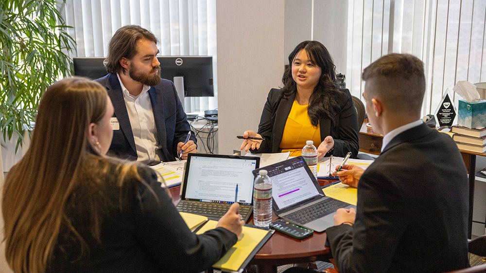 Four Law students sitting around a table with computers talking