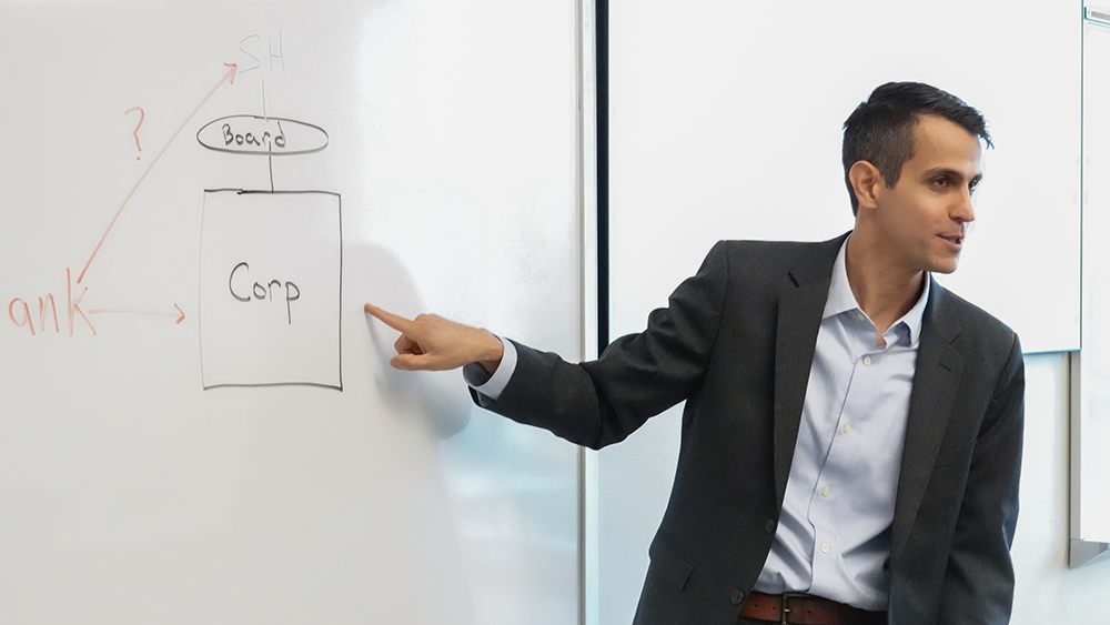 An instructor pointing to a diagram on a whiteboard