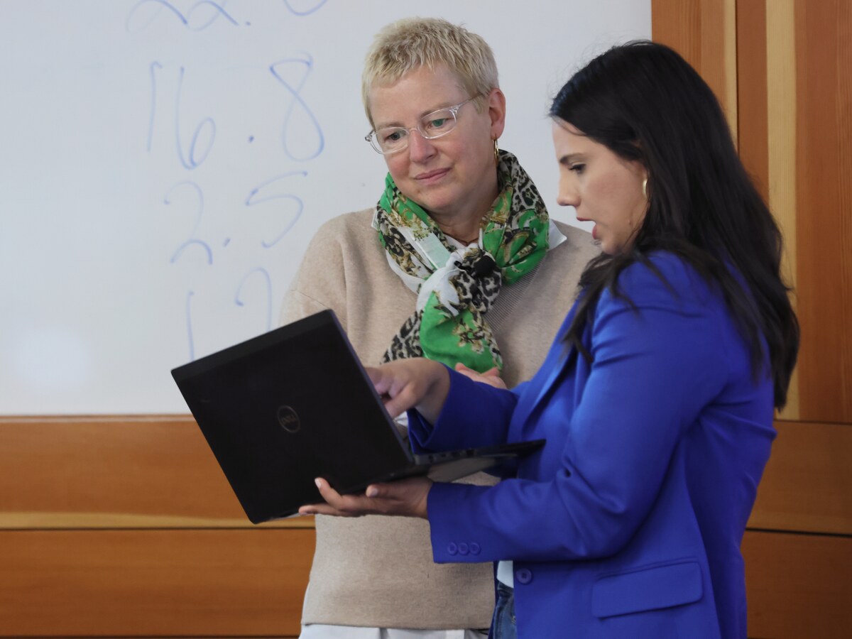 A faculty member reviews a laptop with a student.