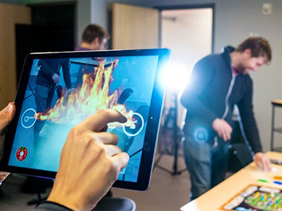 A tablet displays a game while people test it nearby.