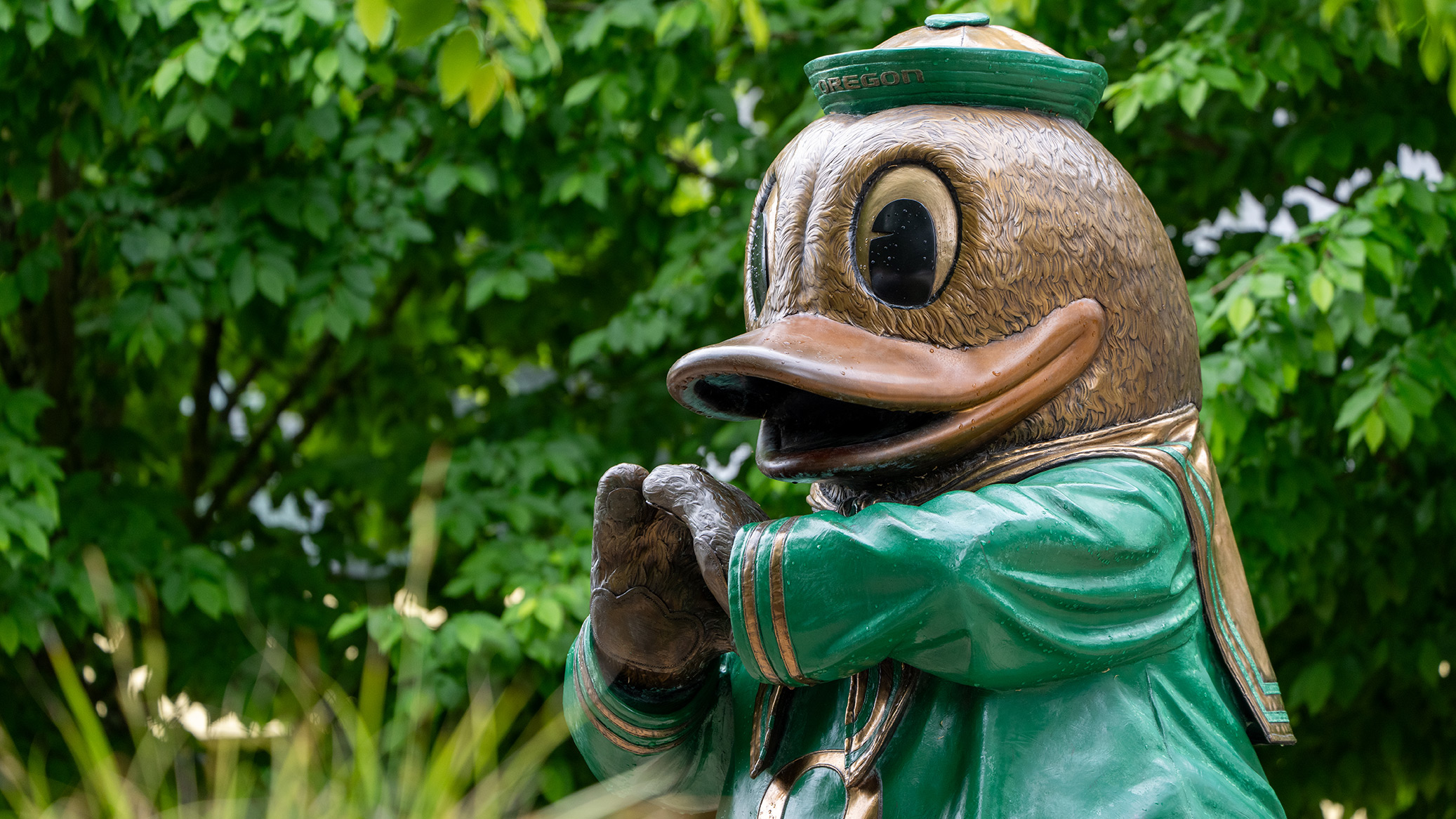 Bronze Oregon Duck statue in a green sailor suit, hands clasped.