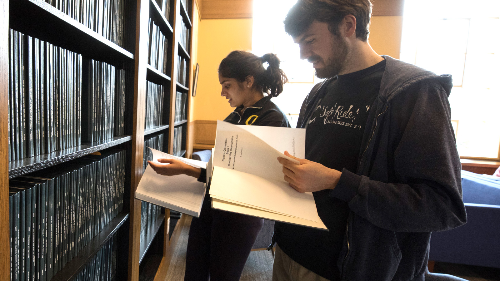 Clark Honors College students look at thesis on the wall of the library inside Chapman Hall.