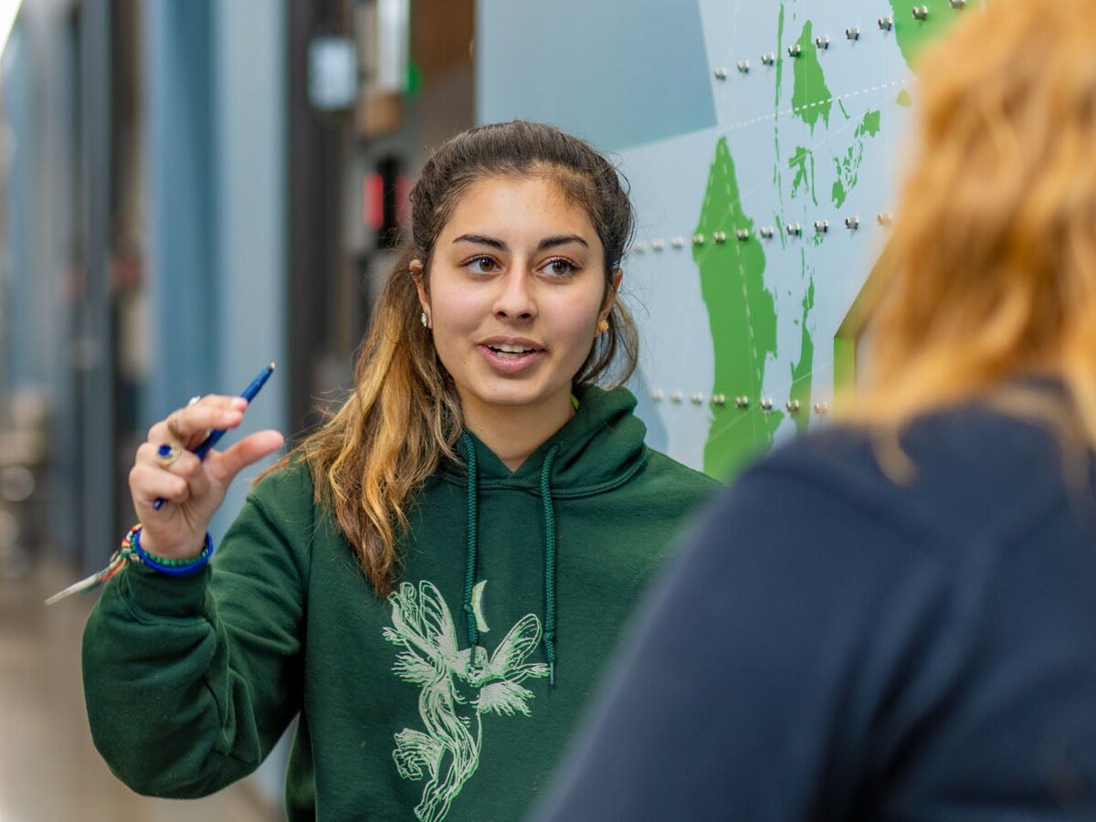 A student talks with a career adviser beside a world map.
