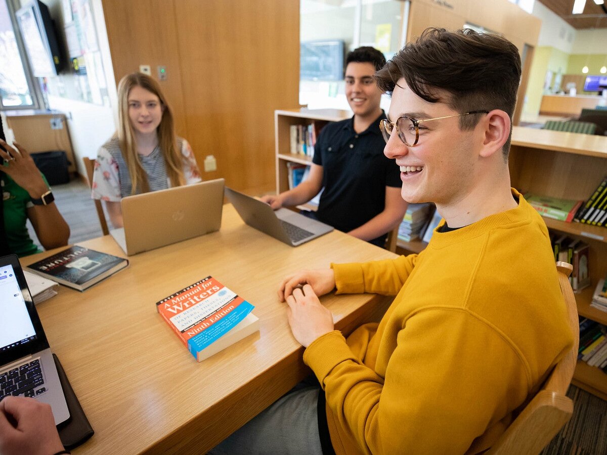 Students work together around a library table.