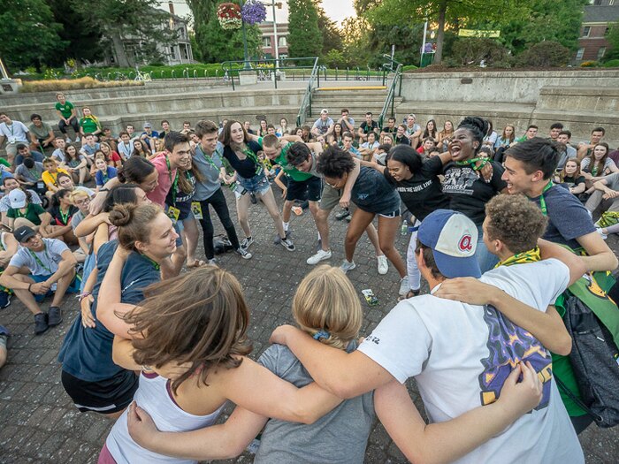Students form a circle during an outdoor campus activity.