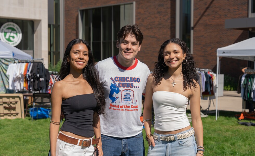 Three students stand together at the EMU Flea Market.