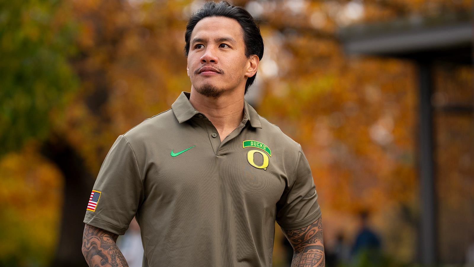 A student veteran proudly wearing a UO branded shirt, with a US flag on a sleeve.