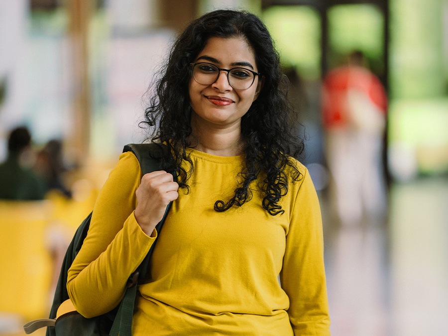 An international student wearing a yellow shirt and backpack.