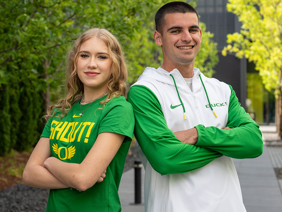 Two students wearing UO branded clothing, smiling towards camera.