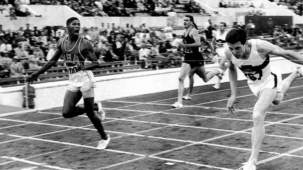 Otis Davis and other runners crossing the finish line on the track