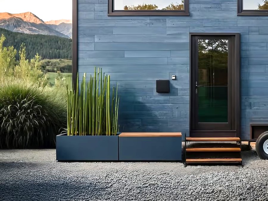 A small blue structure with planters sits before a mountain landscape.