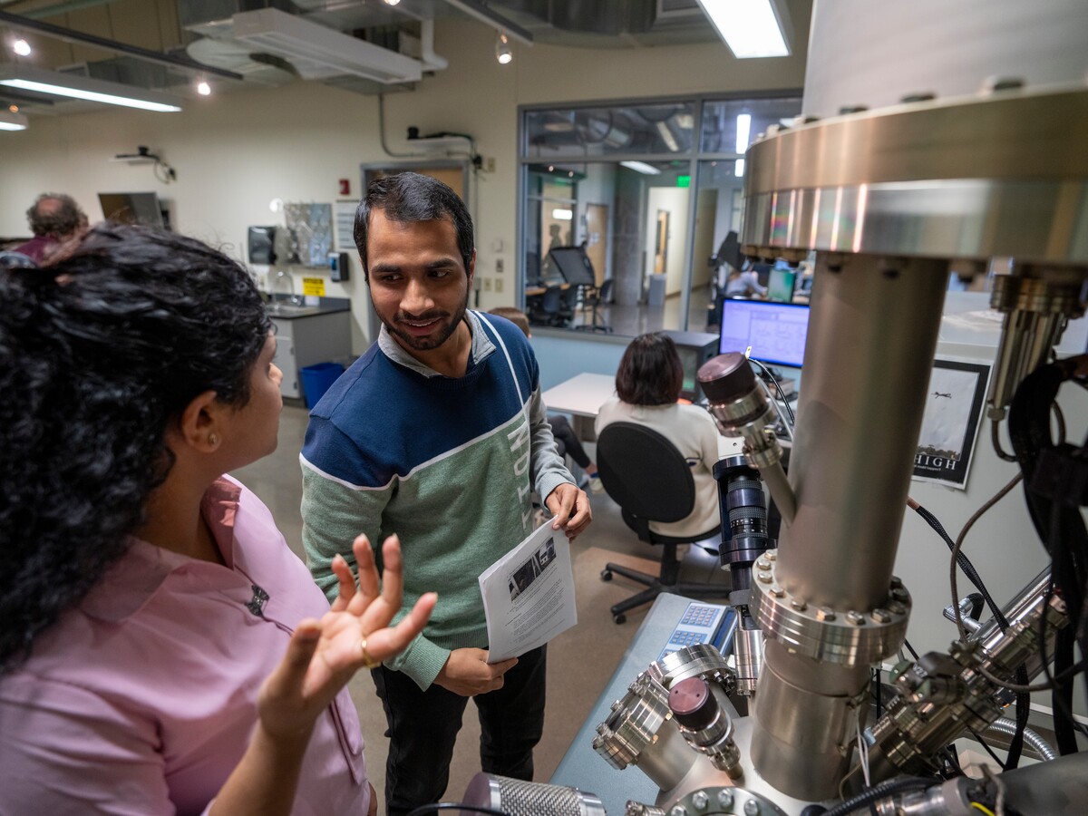 Two researchers work beside an electron microscope in the CAMCOR facility.