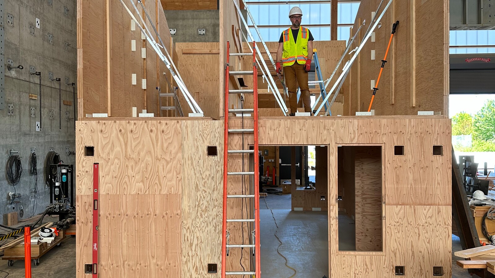 A researcher stands on the second story of an under construction mass timber house prototype.