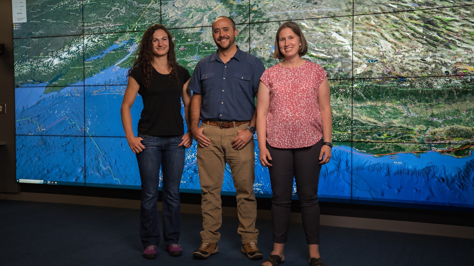 Researchers stand in front of a large map of the Pacific Northwest.