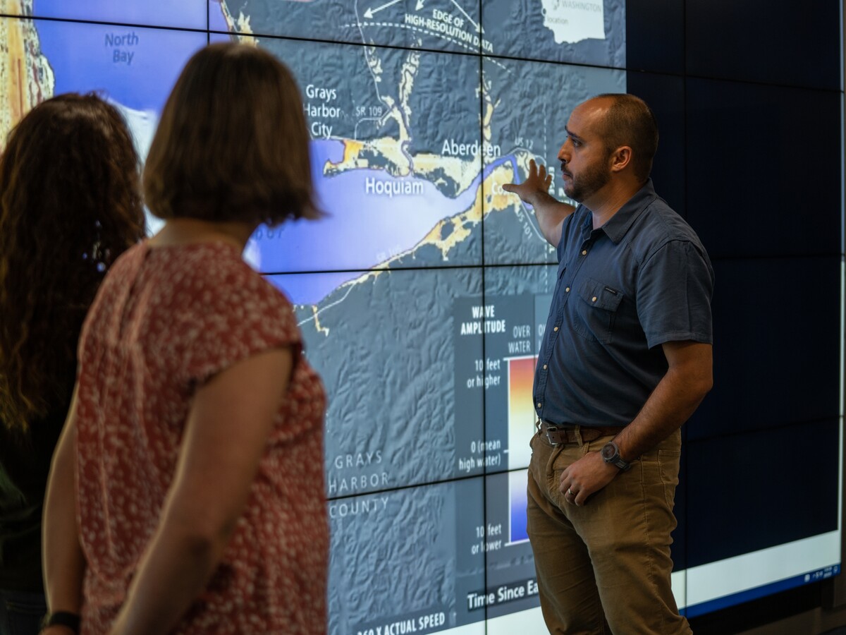A researcher points to a coastal map display.