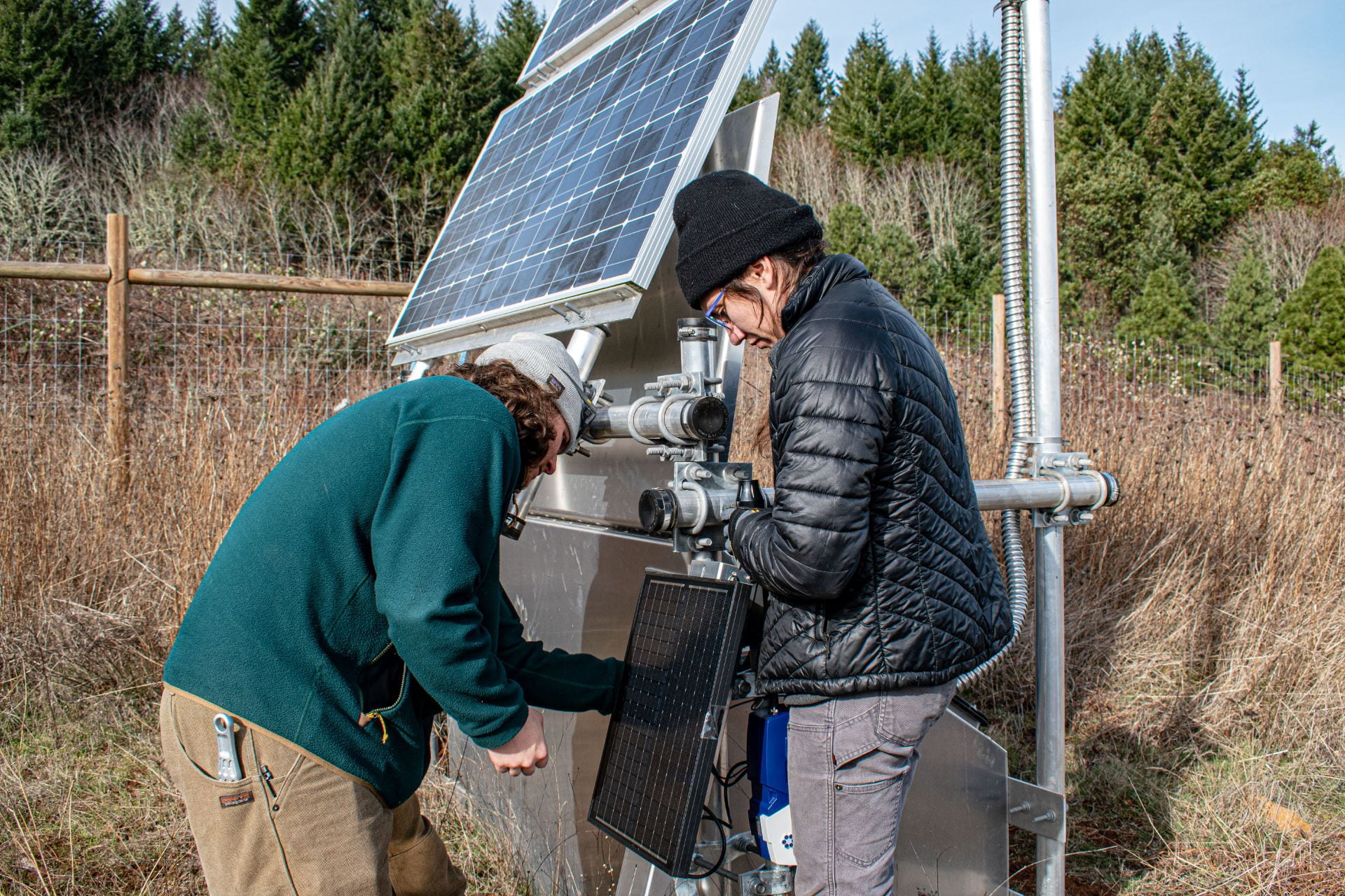 Two researchers install a solar-powered wildfire camera station.