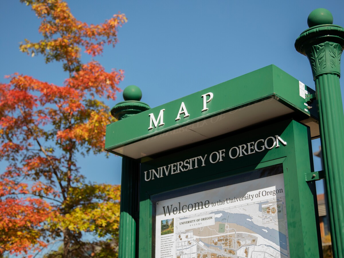 A campus map kiosk stands beneath autumn trees.