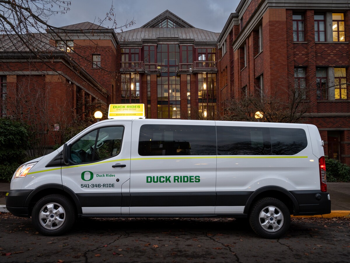 A Duck Rides van is parked outside a campus building.