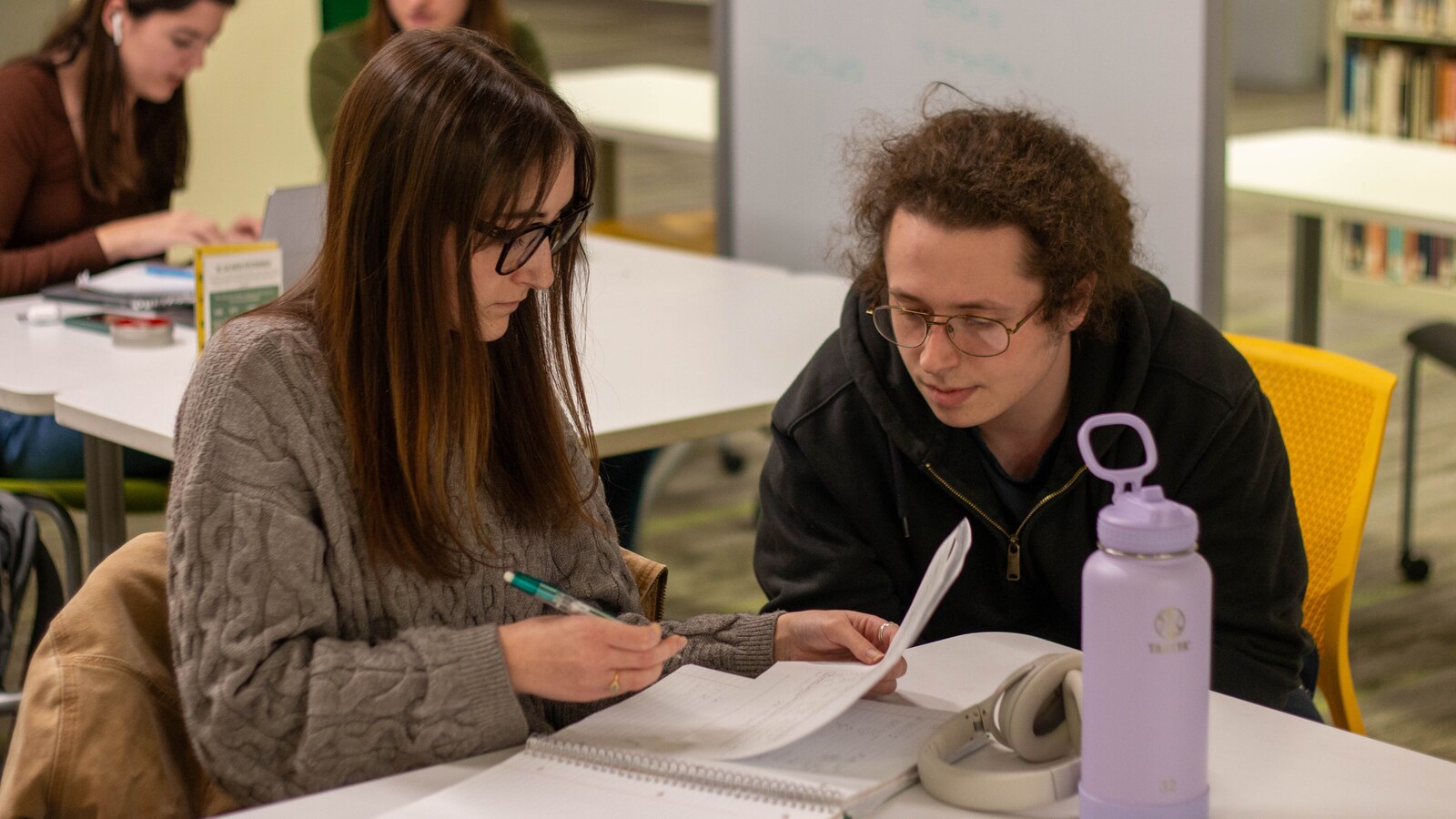 Students study and talk together at tables.