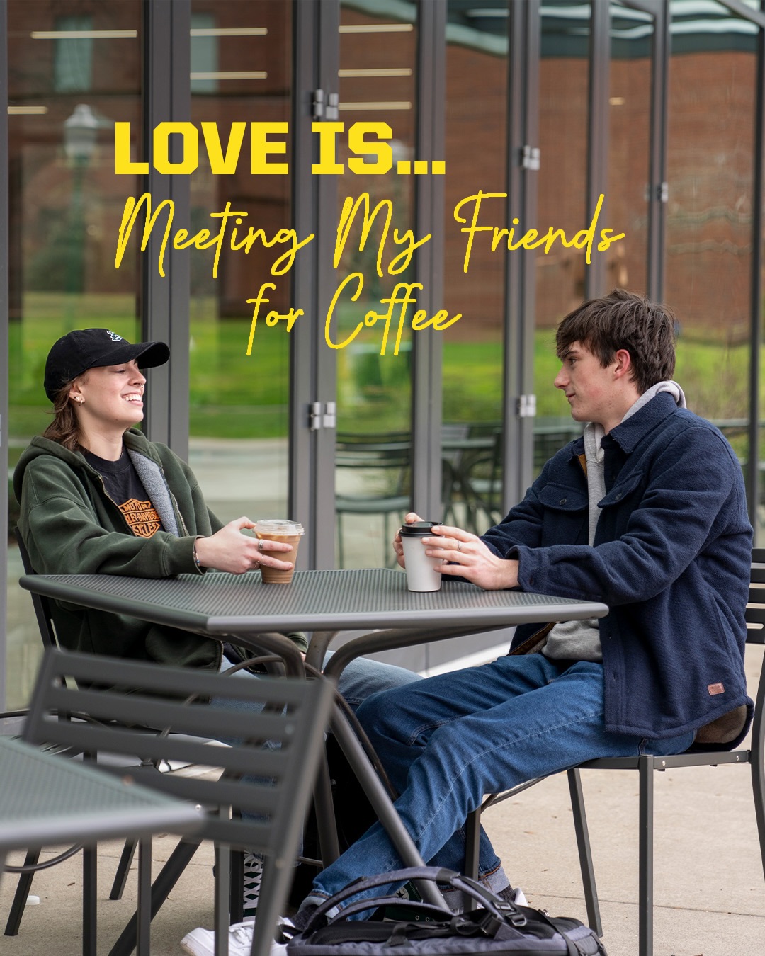 Two students sit at an outdoor table with coffee.