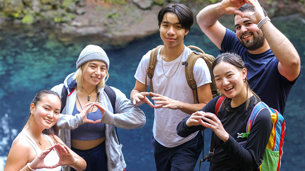 Students gather beside a forest pool during an outdoor adventure.